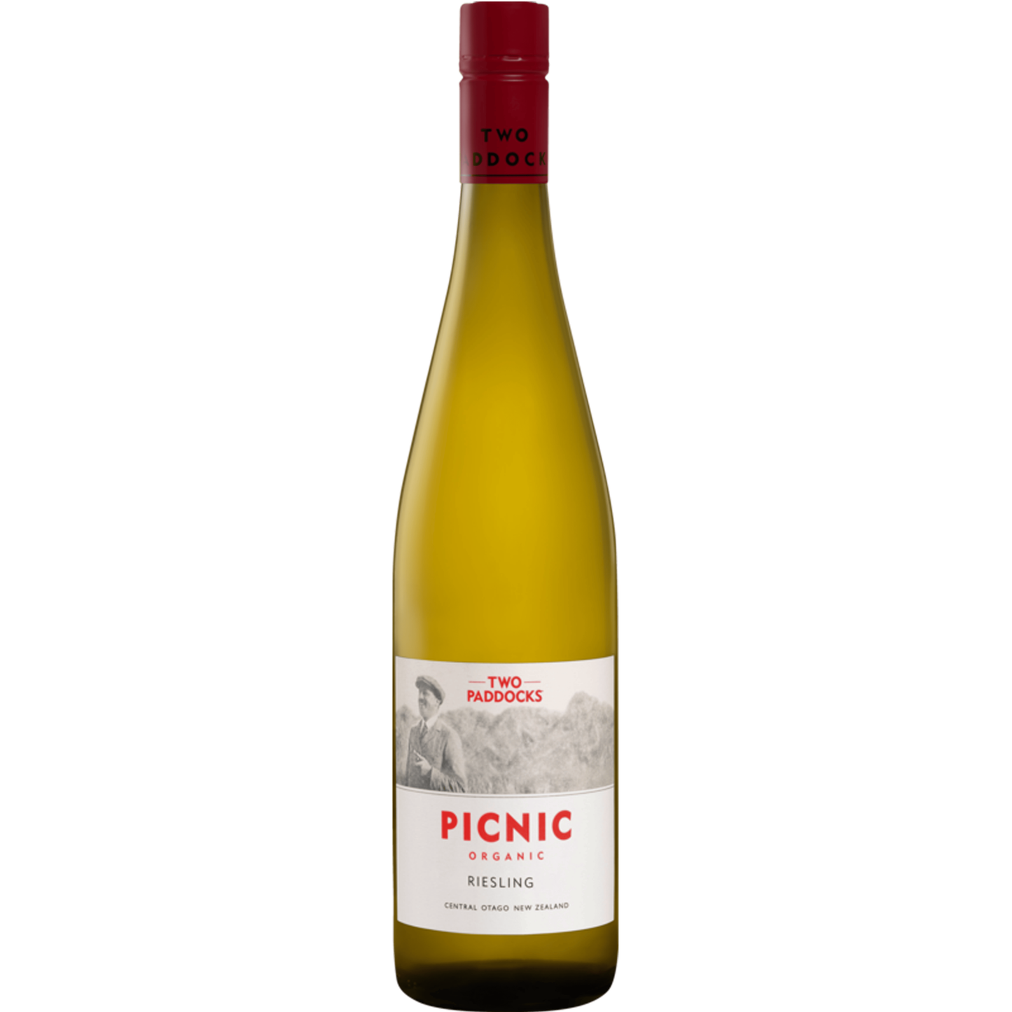 A bottle of Two Paddocks Picnic Organic Riesling white wine, featuring a pale golden-yellow liquid, a white label with red and black text, and a dark red screw cap, set against a solid green background.