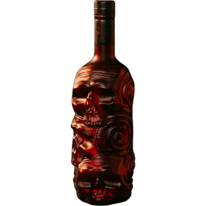 A dark glass bottle with an intricate carved skull and floral design on the front, filled with a deep red liquid, shown against a plain white background.