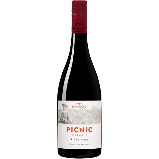 A bottle of Two Paddocks Picnic Organic Pinot Noir red wine against a solid green background.