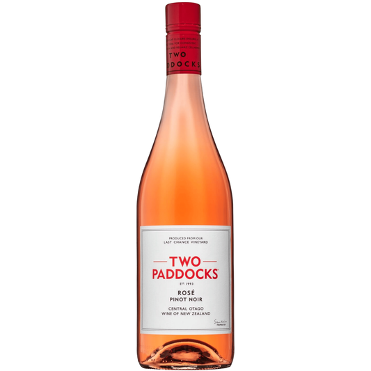 A bottle of Two Paddocks Rose Pinot Noir wine against a solid green background. The bottle contains a pinkish-amber liquid, has a white label with red and black text, and a red foil neck seal.